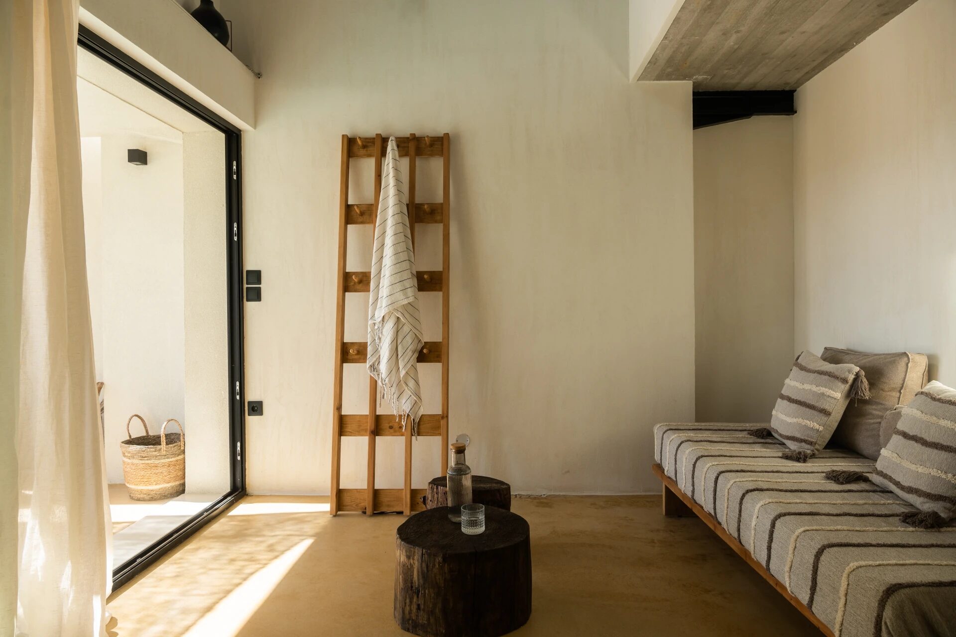 Chora View Suite interior — wooden ladder, striped linen daybed, hand-finished plaster walls