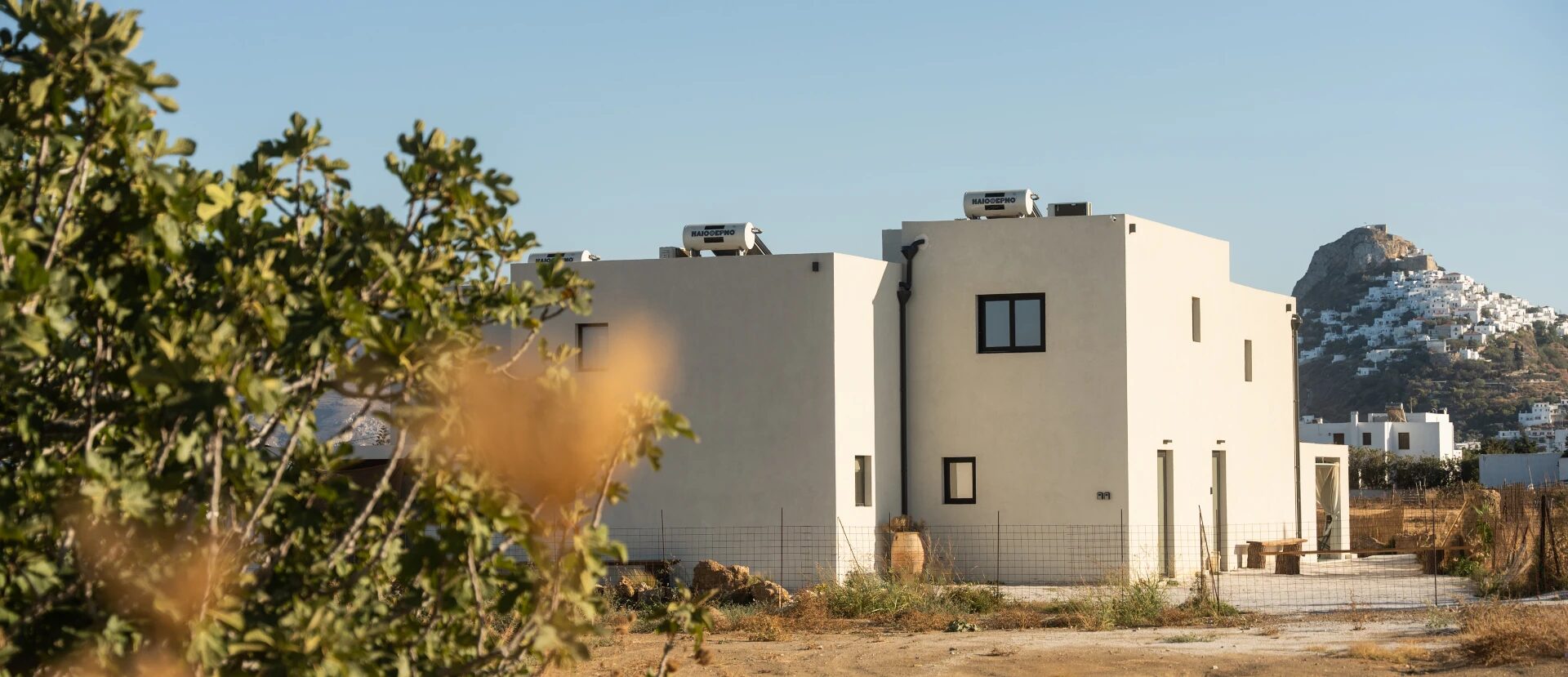 Theta Skyros — the cubic white architecture of the property at golden hour with the historic village of Chora on its hilltop in the distance