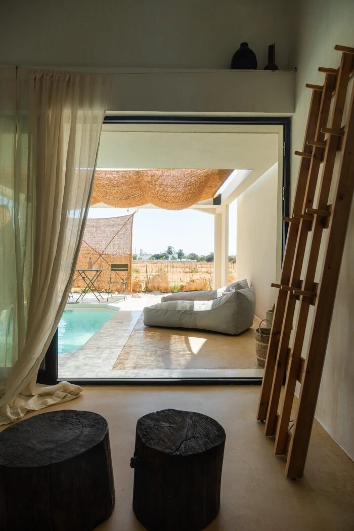 Sea View Suite interior — sheer linen curtain framing the pool and the open horizon beyond