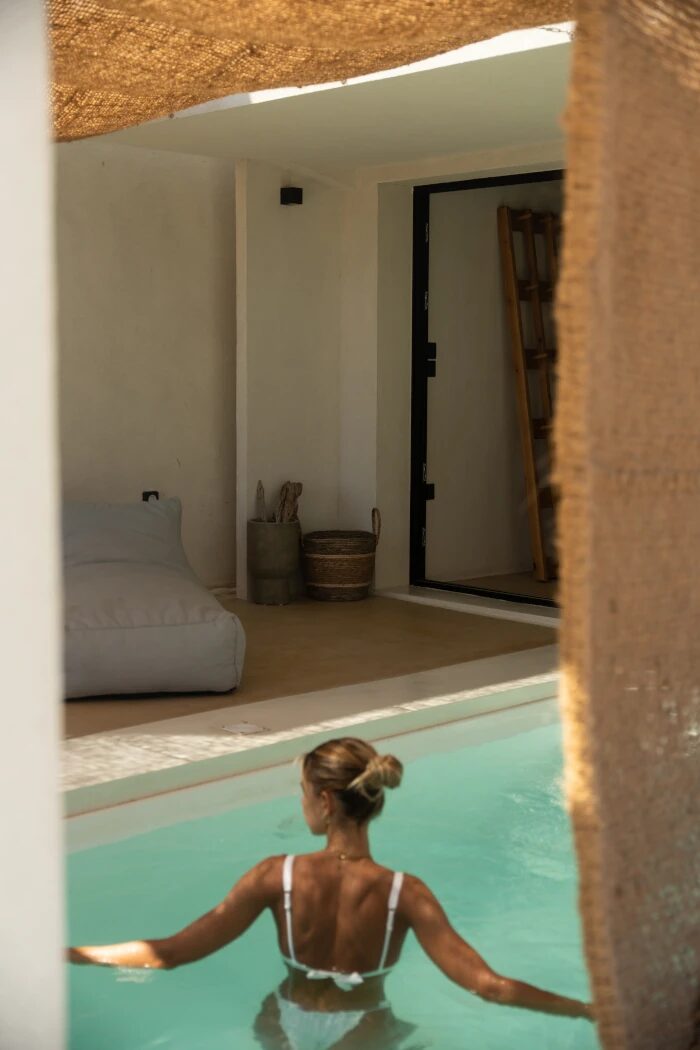 Private pool of the Sea View Suite — guest in the water looking back through the open sliding door into the suite interior