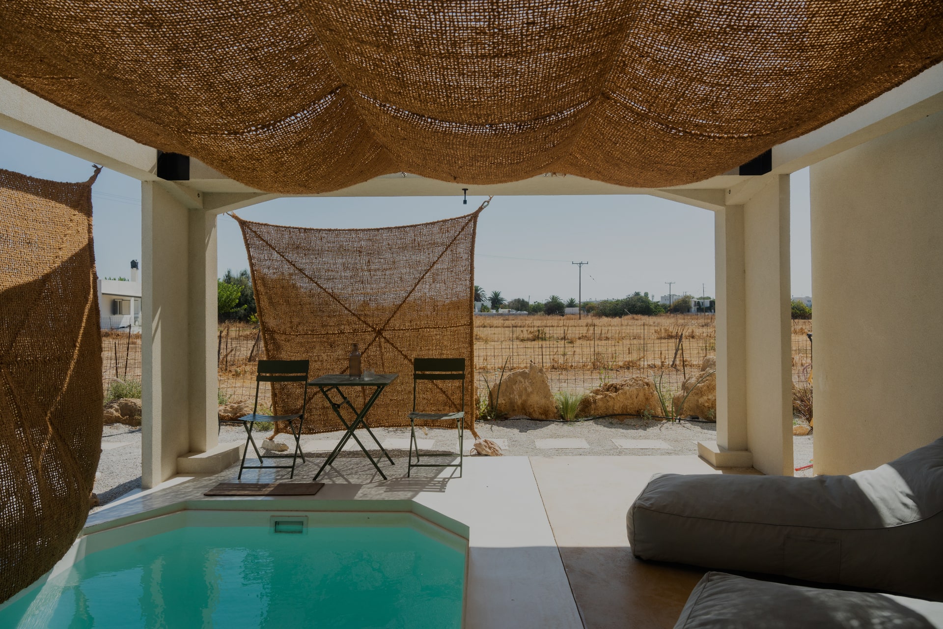 Sea View Suite terrace — pool corner with bistro chairs and shaded outdoor lounge, opening onto the open Skyrian landscape